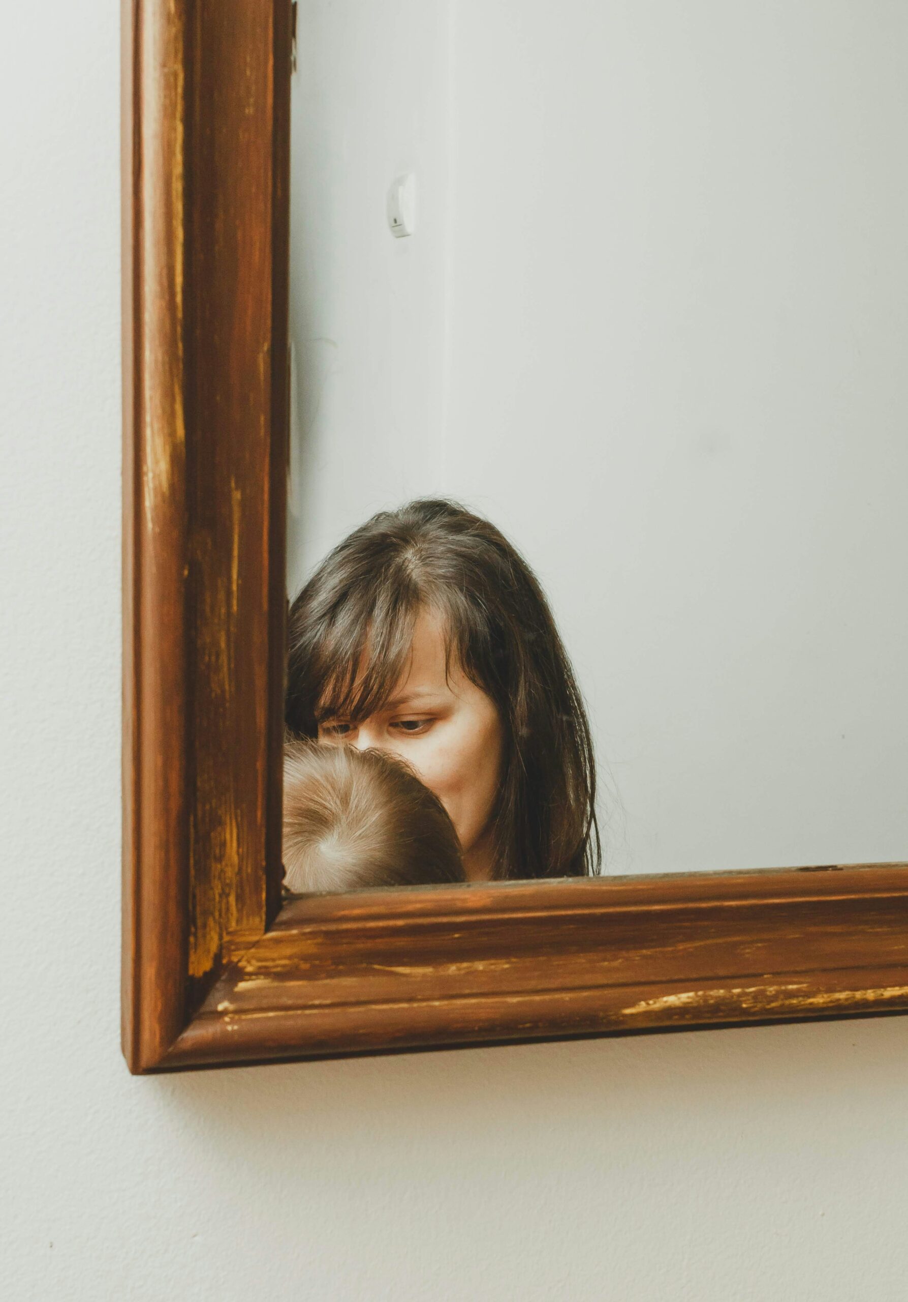 Mujer sosteniendo a su bebé frente al espejo, reflejo de padres narcisistas.